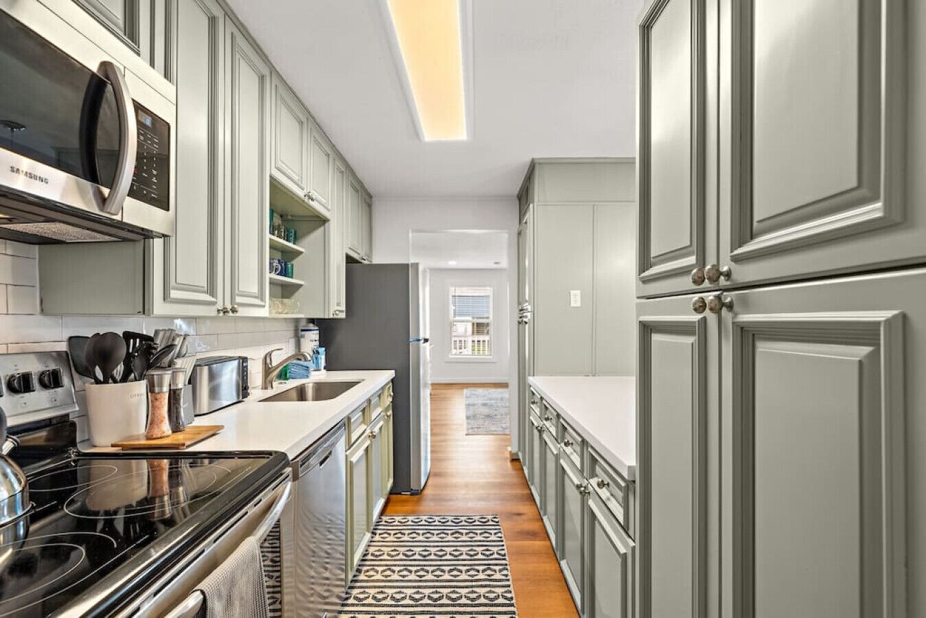 A modern kitchen with white cabinets, a stainless steel stove, and a microwave.