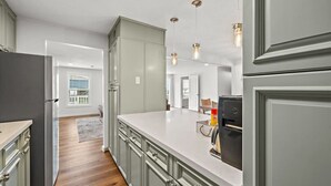 A modern kitchen with grey cabinets, a white countertop, and pendant lighting. - Relax in Beachside Comfort with Stunning Views (Galveston)