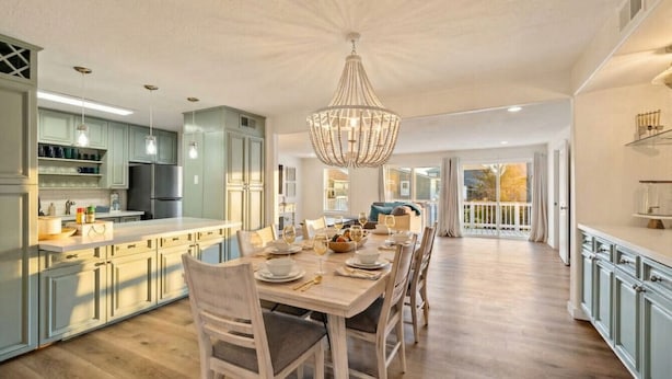 A spacious kitchen with a dining area, featuring a large island, modern appliances, and a chandelier. - Relax in Beachside Comfort with Stunning Views (Galveston)