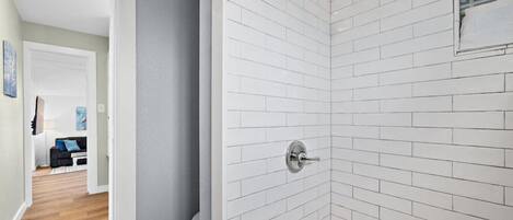 A modern bathroom with white subway tiles, a shower, and a bathtub.