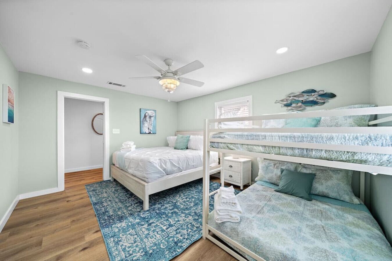 A bedroom with bunk beds, a ceiling fan, and a blue patterned rug.