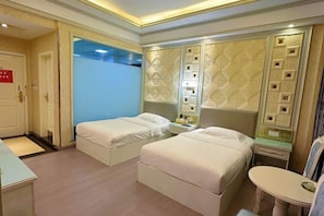 A hotel room with two beds, a small table, and a chair.