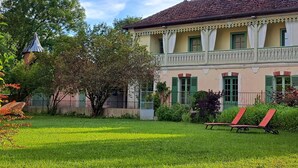 A two-story building with a balcony, green shutters, and a garden with a lawn and a bench. - VILLA DES PROMENADES, 5* atypical in a National Forest Park, European Ecolabel (Vanvey)