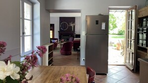 A modern kitchen with a built-in refrigerator, a dining area with a wooden table, and a living room with a fireplace. - VILLA DES PROMENADES, 5* atypical in a National Forest Park, European Ecolabel (Vanvey)