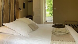 A bedroom with a bed, pillows, a blanket, a hanging light fixture, and a wooden wall art piece. - VILLA DES PROMENADES, 5* atypical in a National Forest Park, European Ecolabel (Vanvey)