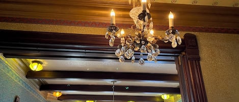A grand chandelier with multiple candles, ornate ceiling patterns, and a large stained glass window.