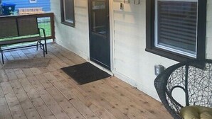 A covered porch with wooden flooring, a bench, a chair, and a door with a window. - Luxurious and peaceful (Topeka)