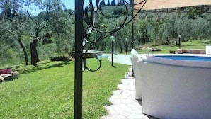 A pool area with a stone pathway leading to a white pool, surrounded by a grassy landscape and trees. - FUCCIOLI II (Carmignano)