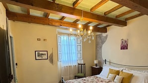 A bedroom with a bed, a chandelier, a window with curtains, and a door. - FUCCIOLI II (Carmignano)