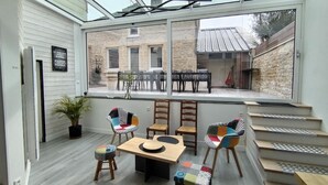 Een modern interieur met een groot raam, houten vloeren en een eethoek met stoelen en een tafel.