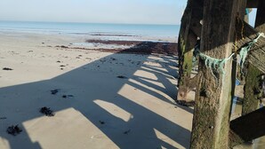 Een strand met een houten constructie, mogelijk een strandhut, en een heldere lucht.