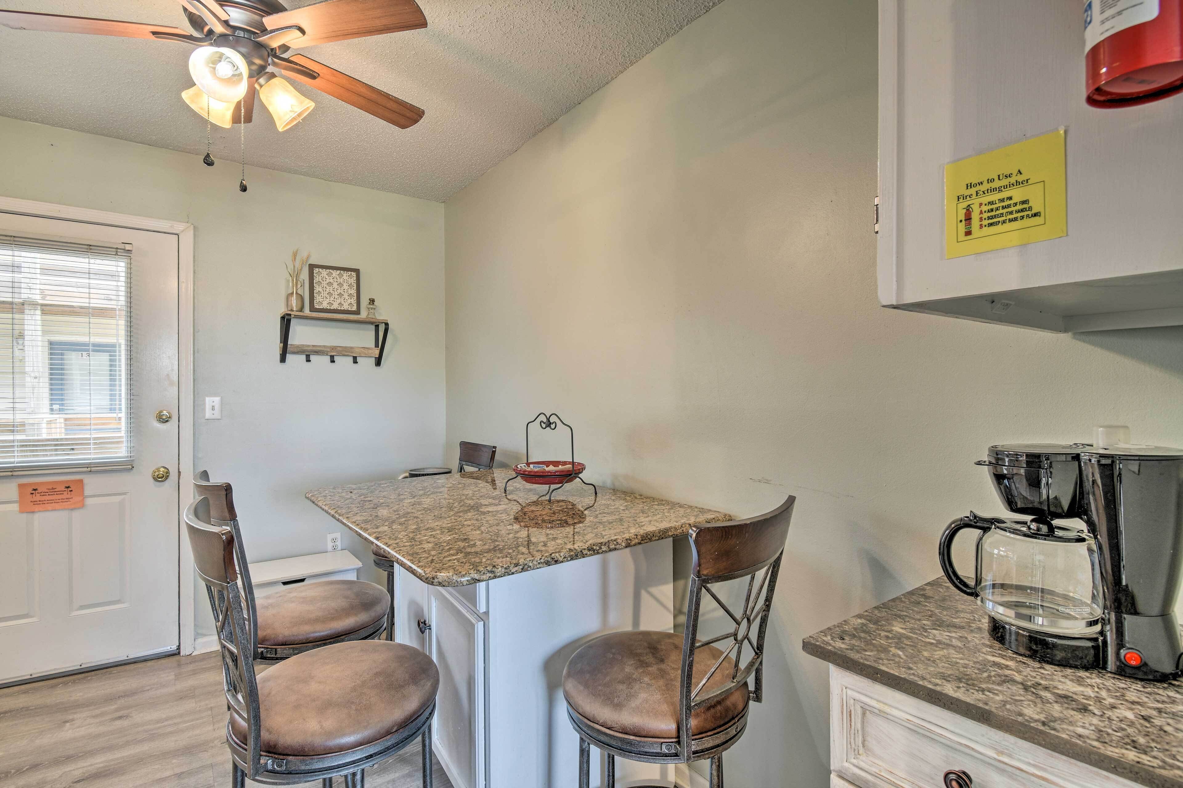 A compact kitchen with a granite countertop, a coffee maker, and a ceiling fan.