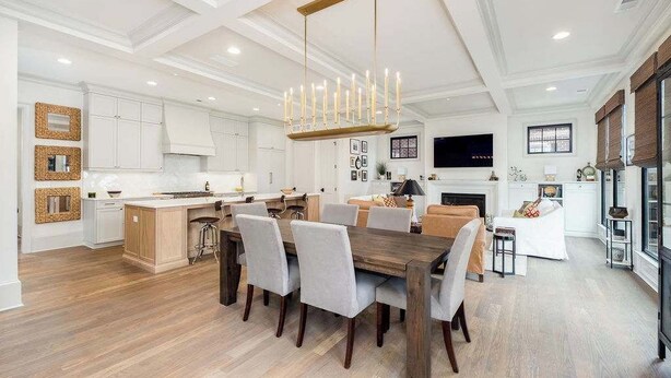 A spacious kitchen with a dining area, wooden flooring, and a modern chandelier.