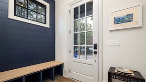 A room with a bench, a door with a window, and a framed picture on the wall.