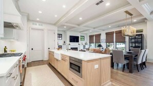 A modern kitchen with a central island, built-in appliances, and a dining area with a chandelier.