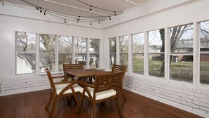 A dining area with a wooden table and chairs, large windows, and a ceiling fan. - Newly Renovated Cozy Rustic Home l 10 min from Truist Park (Smyrna)