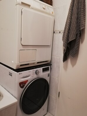 A stacked washer and dryer in a bathroom with a towel hanging on the wall. - Old apartment in top location (Leipzig)