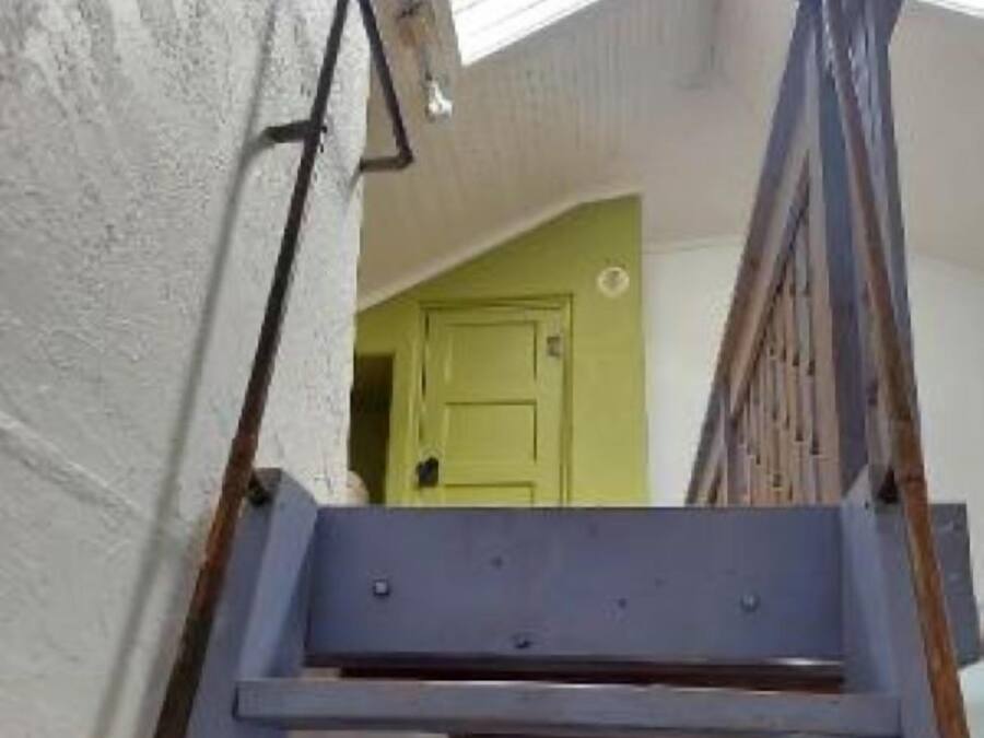 Un escalier avec une rampe métallique menant à un palier.