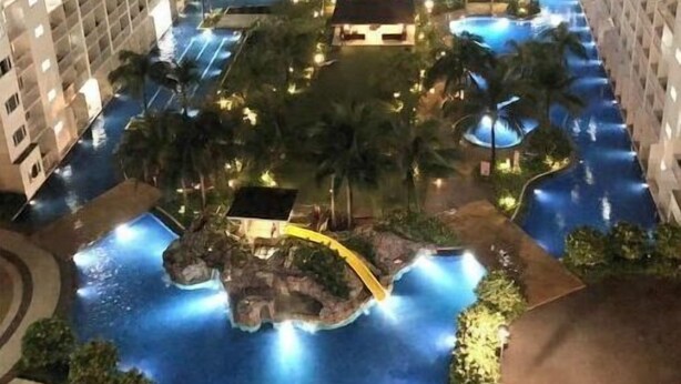 A high-rise hotel with multiple floors, a central courtyard with a swimming pool, palm trees, and a small waterfall feature. - SM Mall of Asia MOA NAIA Pasay Staycation SMX Convention PICC World Trade Center (Pasay)