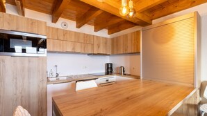 A modern kitchen with wooden cabinets, a stainless steel range hood, a coffee maker, and a wooden dining table. - Le Caribou - Appt 3 chambres proche pistes (Les Angles)