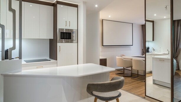 A modern kitchen with white cabinetry, a built-in microwave, and a central island with seating.