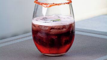 Een glas rode vloeistof met een zoutkorstje op een gestructureerd oppervlak.