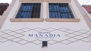 Fachada del Hotel Manadia, con vista despejada a la entrada y la señalización.