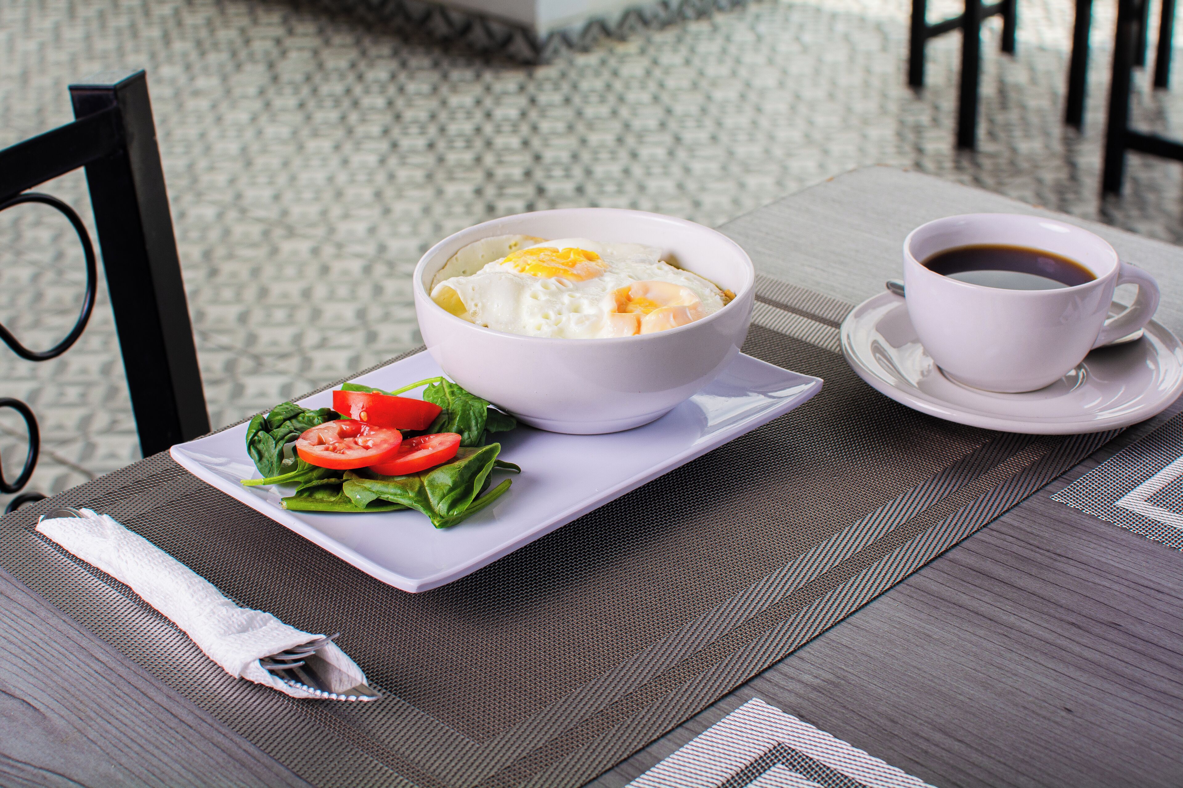 Una mesa con un bol de comida, una taza de café y un plato de verduras.