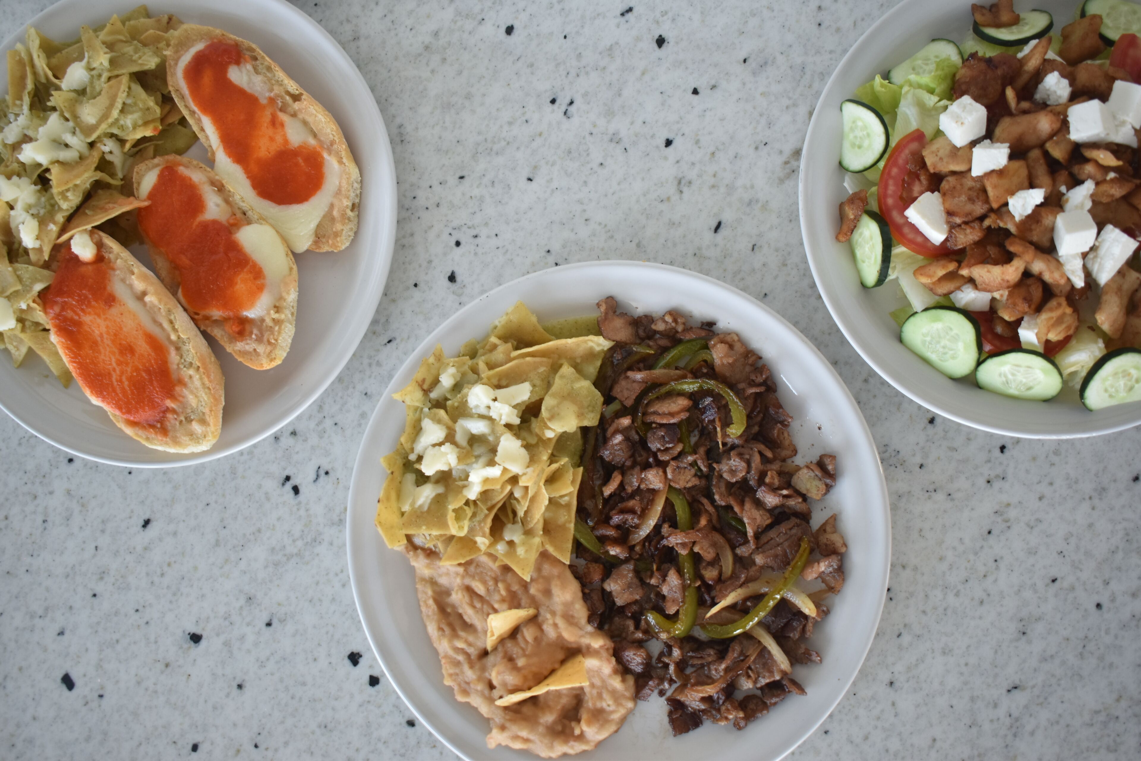 Tres platos de comida con distintos guisos, incluyendo pan, carne y verduras.