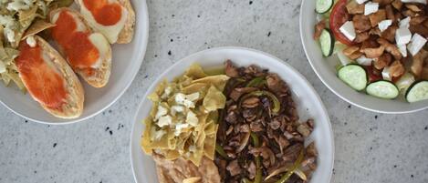 Three plates of food with different dishes including bread, meat, and vegetables.