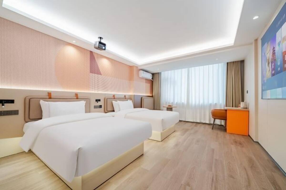 Une chambre d’hôtel avec deux lits, un bureau et une grande fenêtre.
