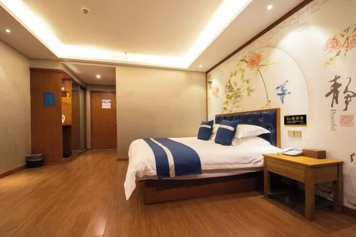 Une chambre d’hôtel avec un lit, une table de chevet et un mur décoré d’œuvres d’art florales.