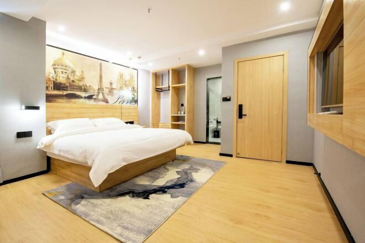 Une chambre moderne avec un grand lit, une armoire en bois et des étagères intégrées.