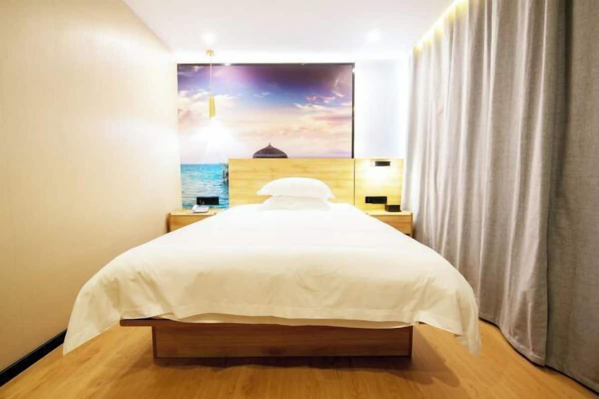 Une chambre d’hôtel avec un lit, une tête de lit en bois, des tables de chevet, une fresque murale et un rideau.