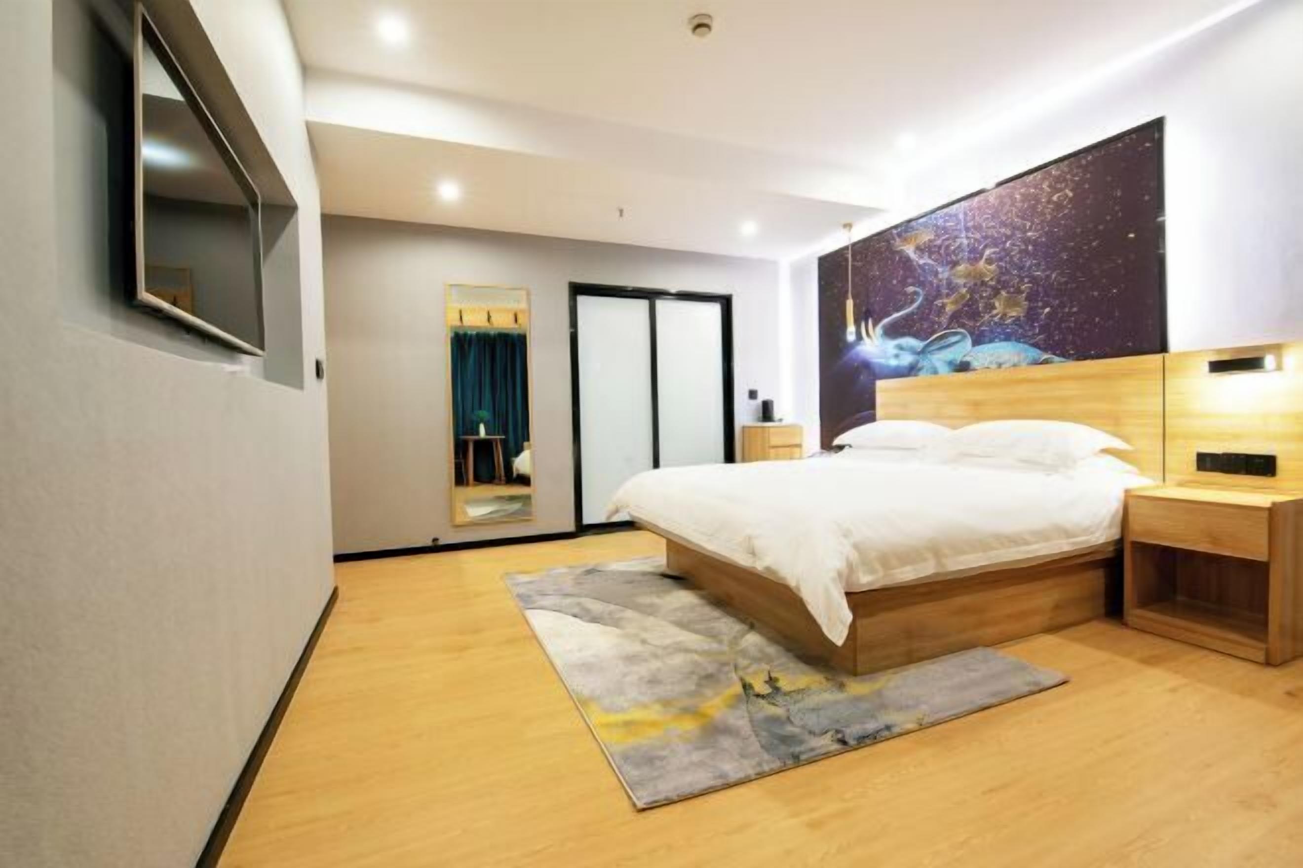 A modern bedroom with a bed, bedside tables, a TV, and a large wall mural.