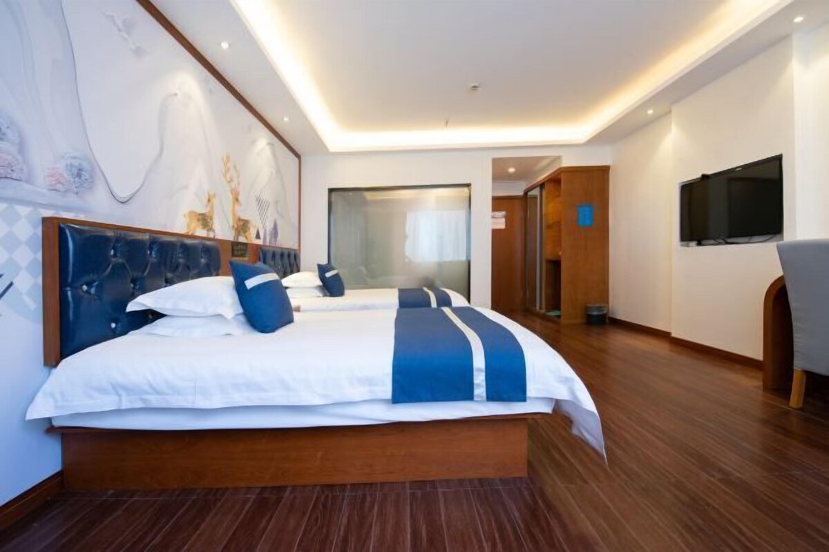 A modern hotel room with a large bed, a TV, and a wooden floor.