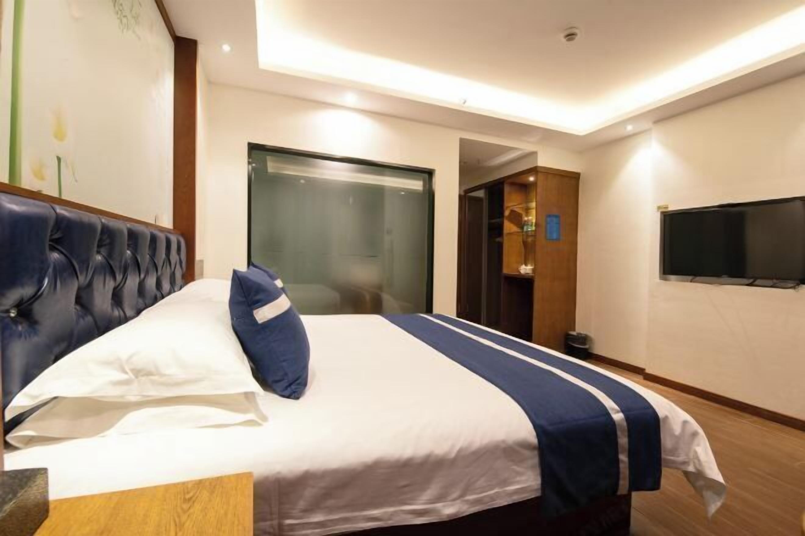 A hotel room with a large bed, a television, and a door leading to a bathroom.