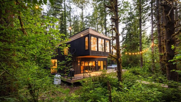 A modern cabin with a deck, surrounded by dense forest. - Pacific Bin - Sauna / Hot Tub / Steam Room (Monroe)
