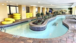 An indoor swimming pool with a tiled edge, yellow floating rings, and a small island with plants.