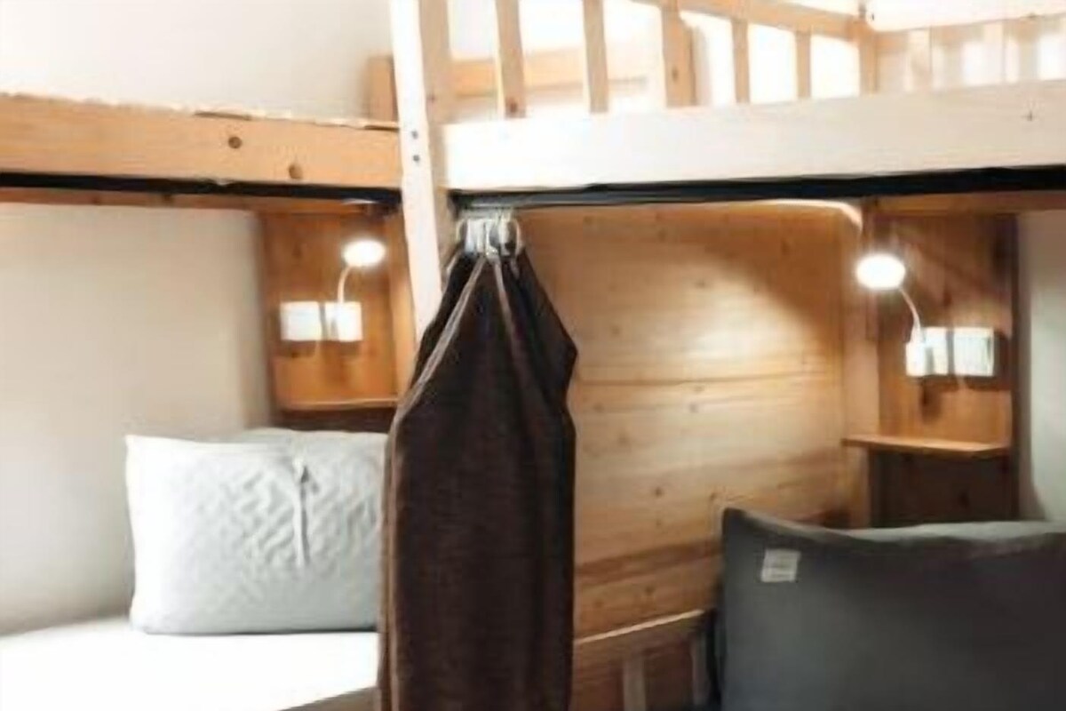 A bunk bed with a mattress, pillows, and a blanket.