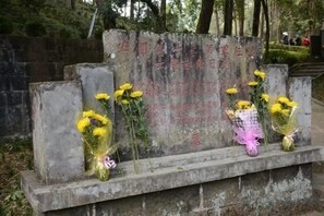 A stone memorial with inscriptions and bouquets of flowers. - Beret B&B (Tengchong)
