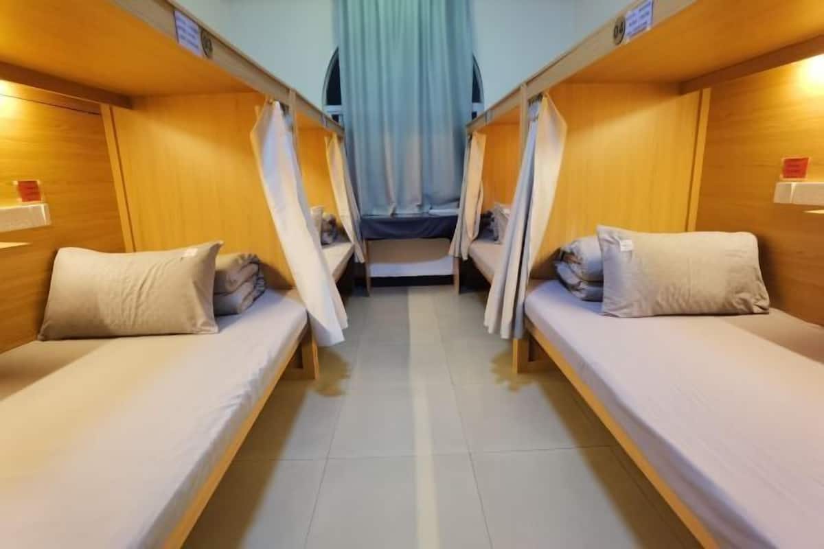 A train compartment with two single beds, wooden walls, and a curtain at the end.