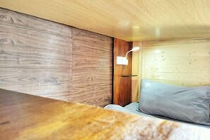 A wooden interior with a bed, a nightstand, and a wall-mounted light fixture. - Beret B&B (Tengchong)