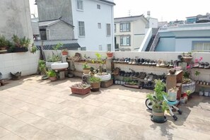 A rooftop with potted plants, a shoe rack, and a small wheelbarrow. - Beret B&B (Tengchong)