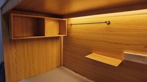 Una pared de madera con un estante y una barra para colgar, una lámpara y un enchufe.