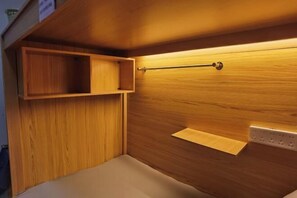 A wooden wall with a shelf and a hanging rod, a light fixture, and a power outlet. - Beret B&B (Tengchong)