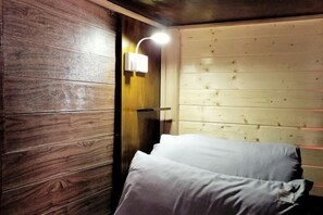 A wooden room with a bed, a wall-mounted light, and a wooden door. - Beret B&B (Tengchong)