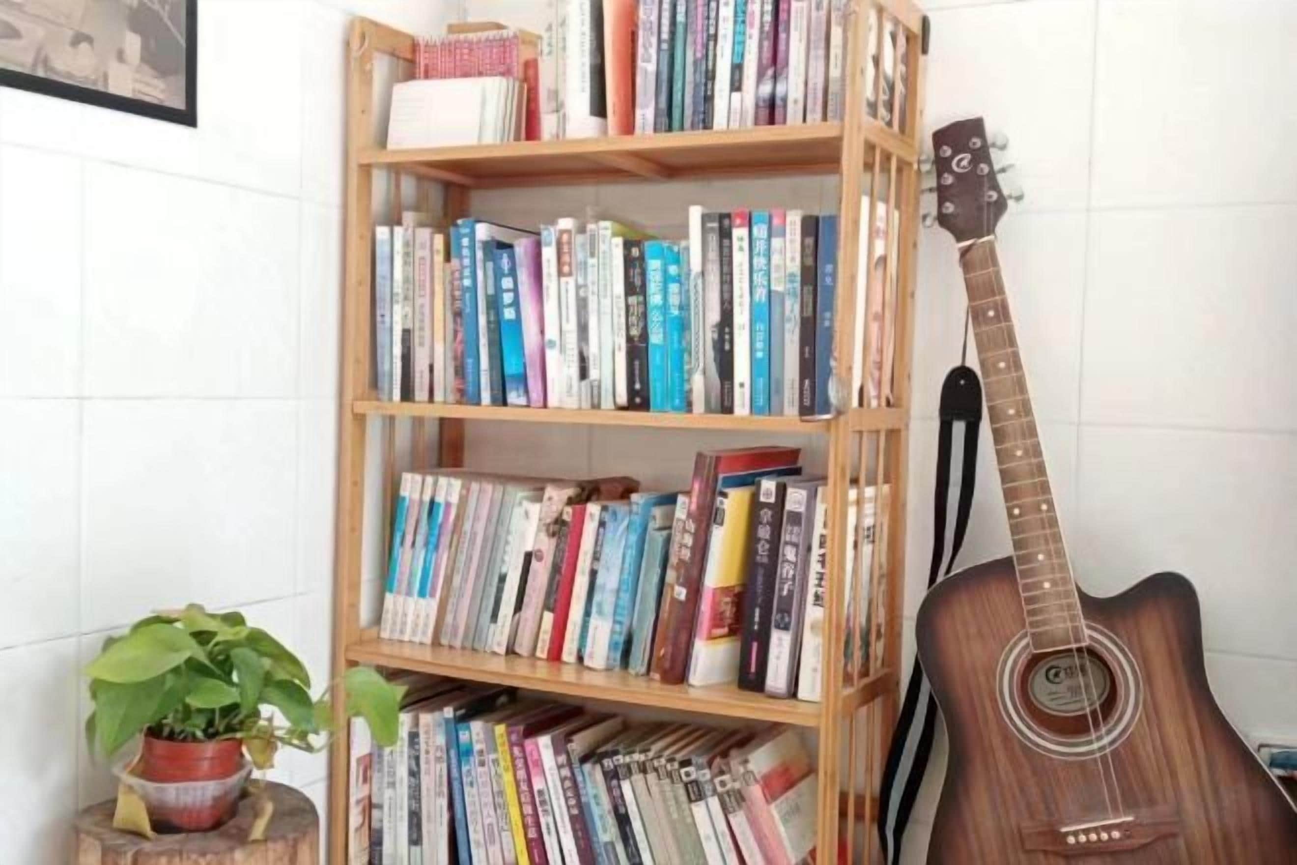 Une bibliothèque remplie de livres, avec une guitare appuyée contre.