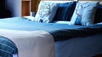 Cama bem arrumada com roupa de cama listrada e almofadas decorativas, uma cabeceira de madeira e uma mesa de cabeceira com um abajur.