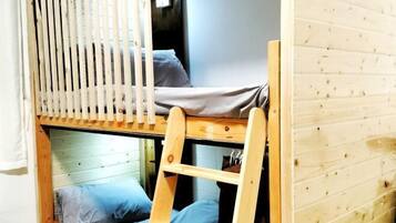 Una cama litera con escalera de madera, una ventana con persianas verticales y una pared de madera.